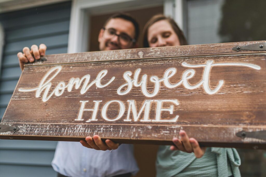 a man and a woman holding a wooden sign that says home sweet home