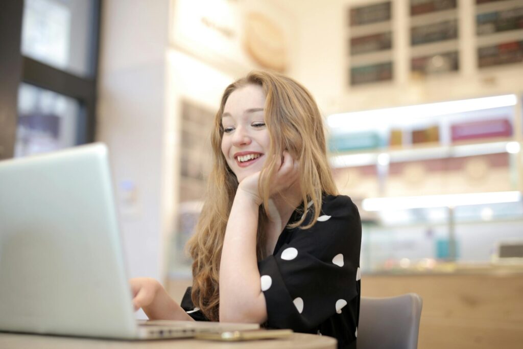 a woman in black and white polka dots dress sitting on chair using a laptop